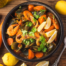 Image of a large bowl of seafood curry with carrots and herbs