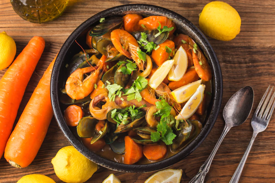 Image of a large bowl of seafood curry with carrots and herbs