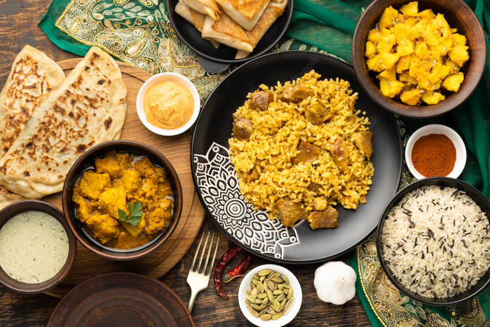 Image of a table covered with Indian curries, rice, breads and vegetables