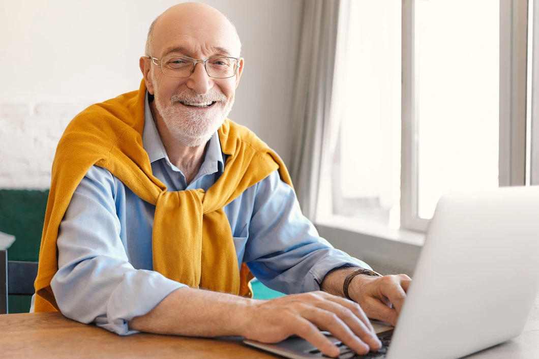 Image of a cheerful mature man smiling happily while on his laptop