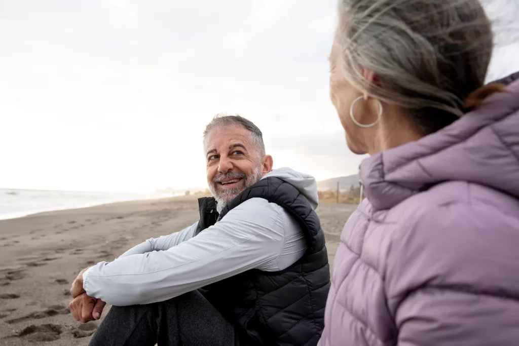 Image of mature-aged friends talking at the beach