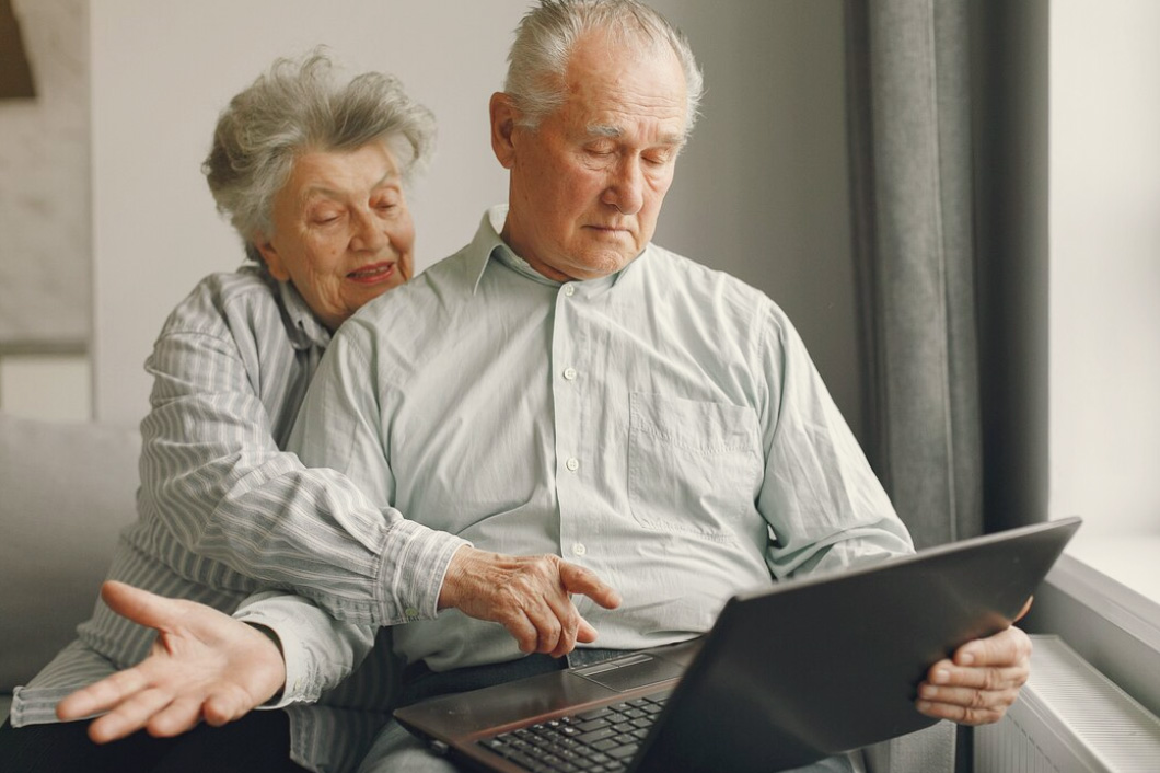 Image of an elderly couple on their laptop. The man is having trouble.